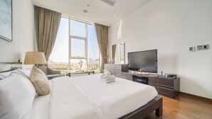 Une chambre d’hôtel dotée d’un grand lit, d’une télévision à écran plat, d’un bureau avec un ordinateur et offrant une vue sur la ville.