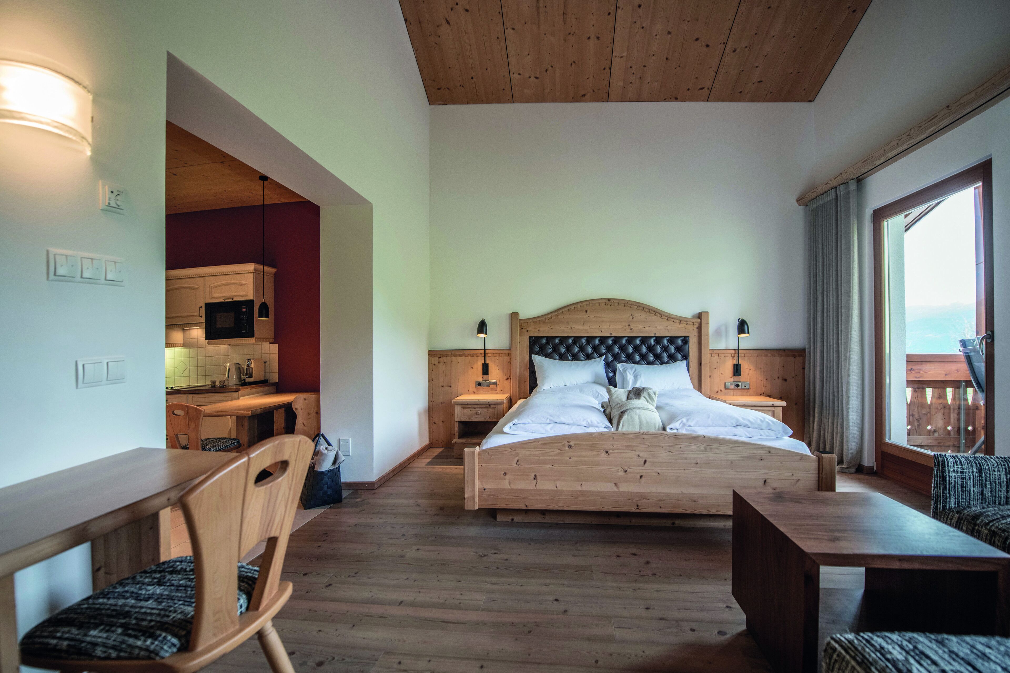 Un dormitorio con una cama y un escritorio de madera, y vistas al exterior a través de una ventana.