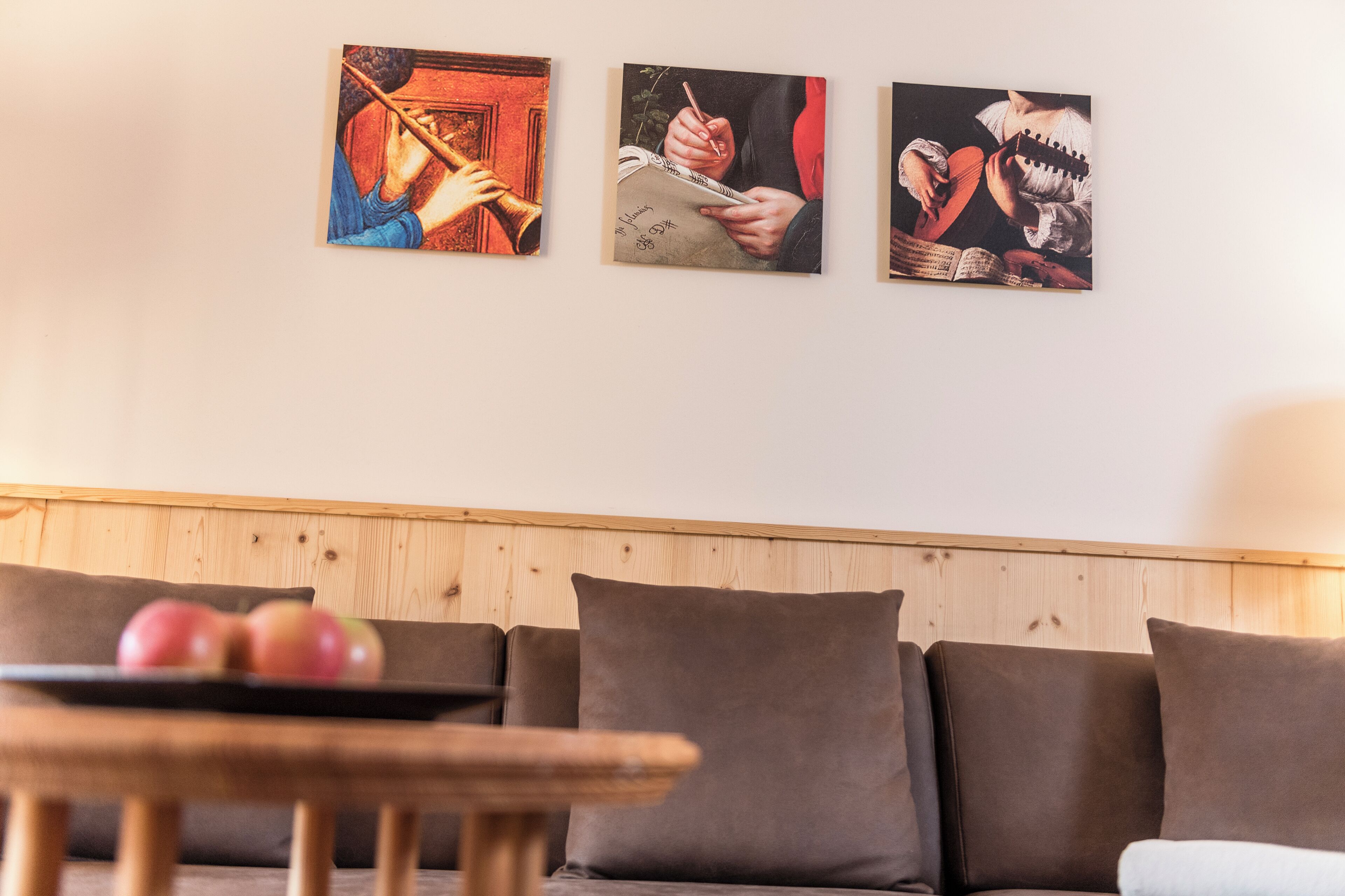 Un salon avec un mur lambrissé en bois, un canapé marron et une table sur laquelle se trouvent des pommes.