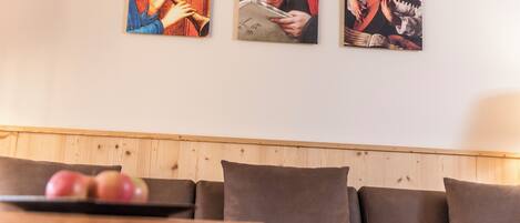 Un salon avec un mur lambrissé en bois, un canapé marron et une table sur laquelle se trouvent des pommes.