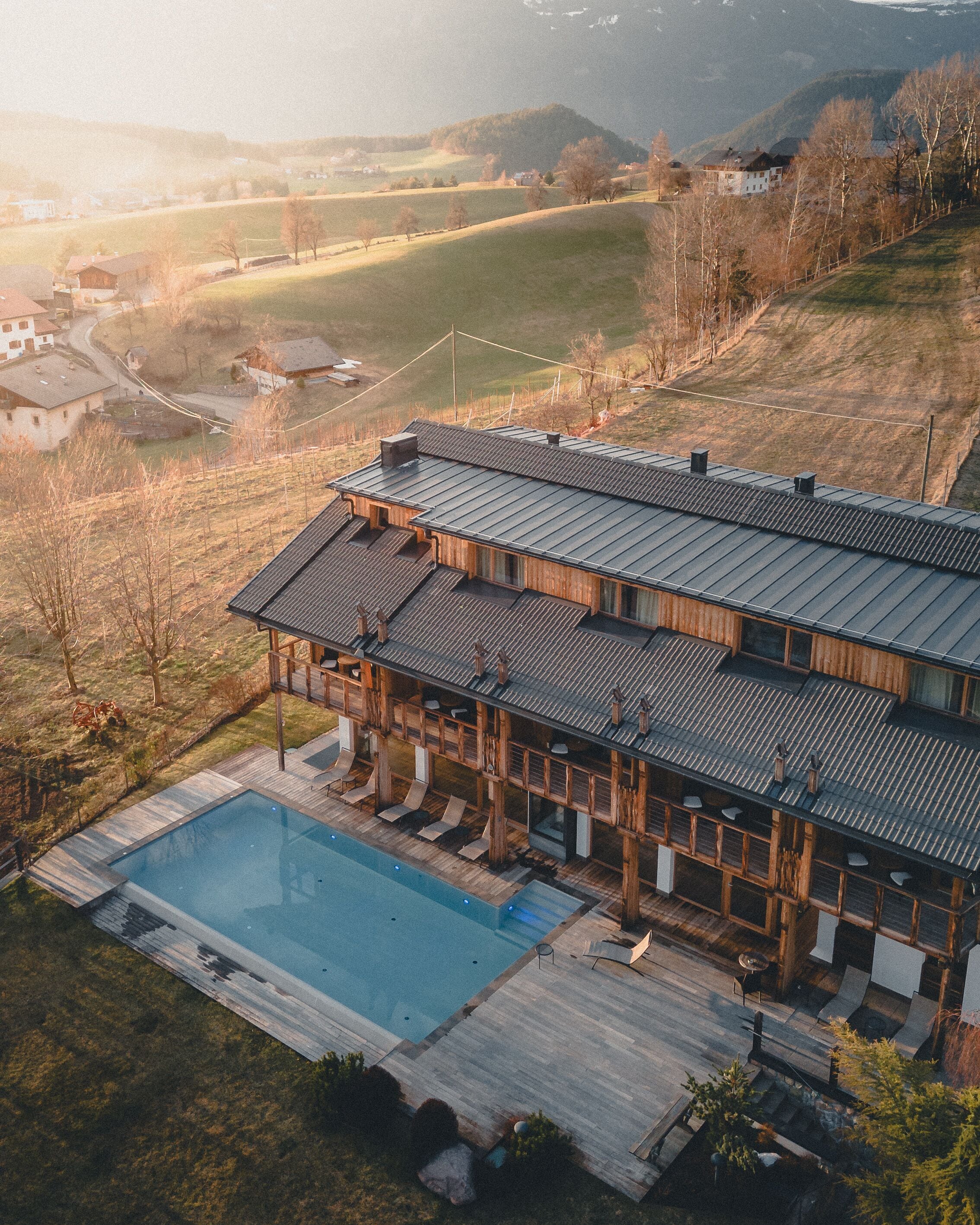 Une maison moderne dotée d’une grande piscine, d’une terrasse en bois et offrant une vue sur le paysage environnant.