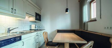 Una cocina funcional con armarios blancos, una mesa de comedor de madera y un banco integrado.