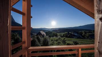 Un balcón de madera con vistas a un paisaje montañoso y un cielo despejado.