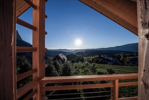 Un balcón de madera con vistas a un paisaje montañoso y un cielo despejado.