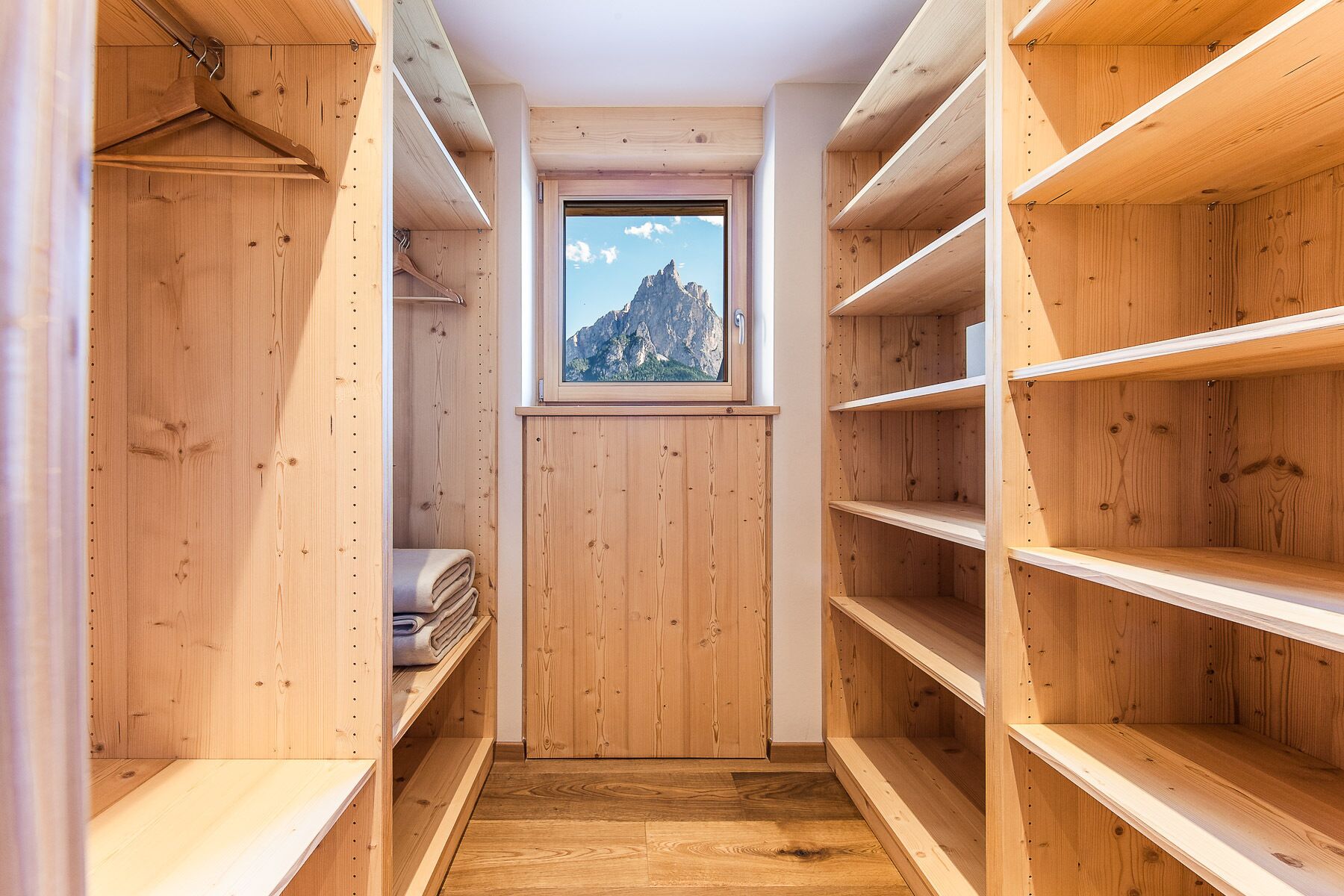 A wooden closet with shelves and a window.