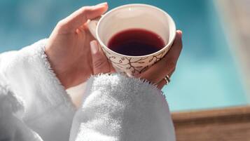 A person holding a cup of tea by a poolside.