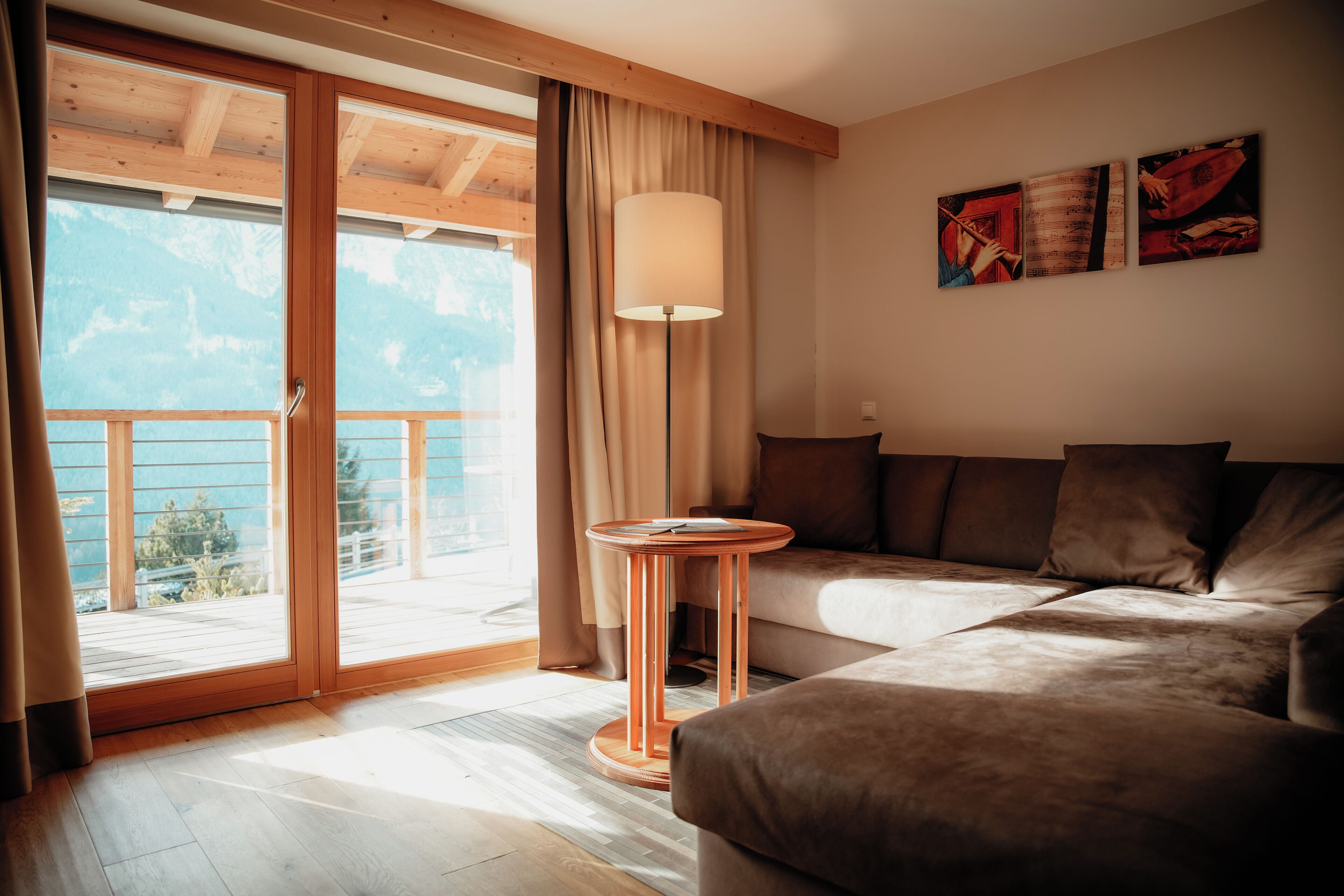 A modern living room with a sofa, a small round table, and a large window with curtains.