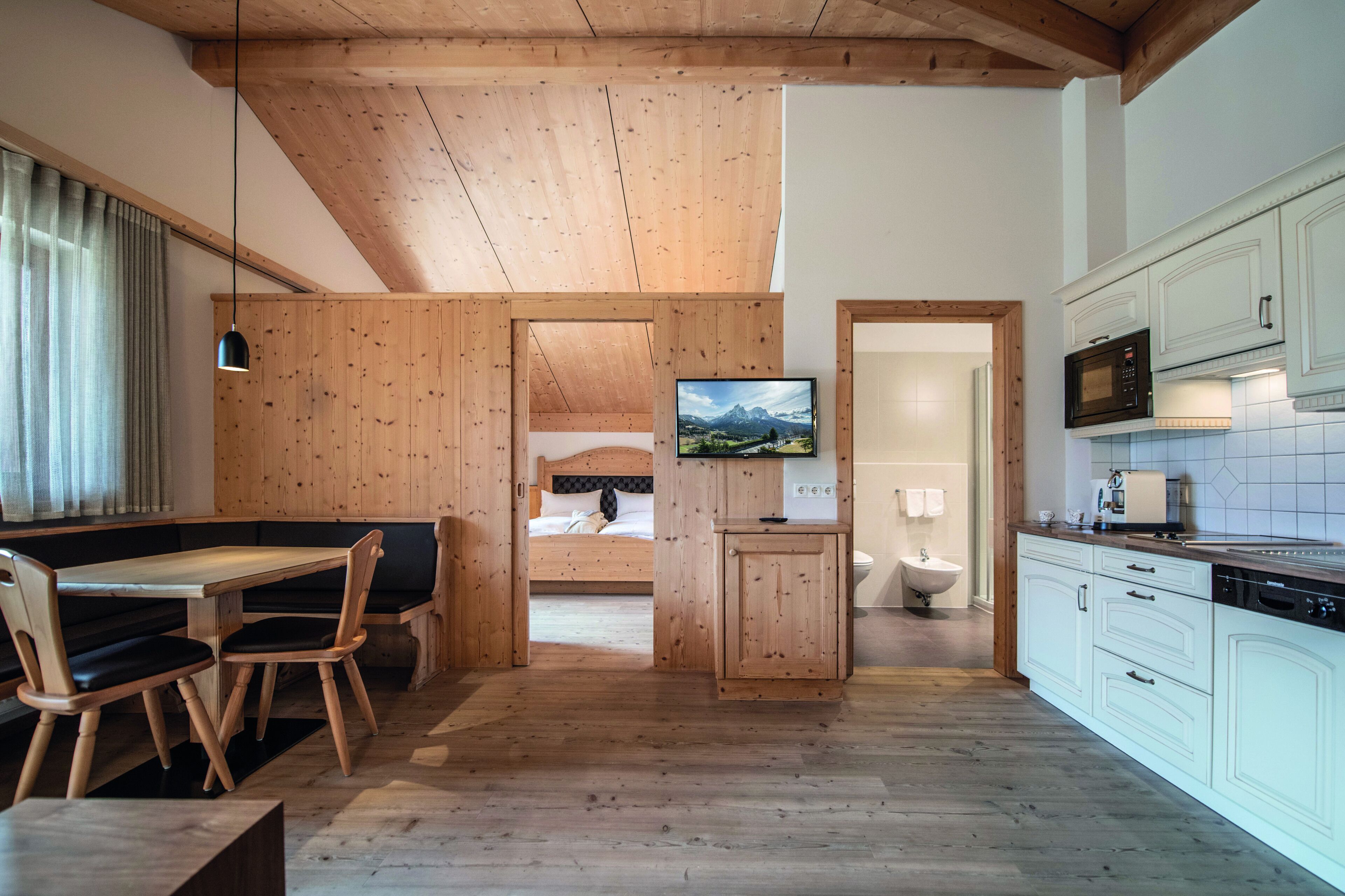 Un interior de madera con comedor, televisor y cocina.