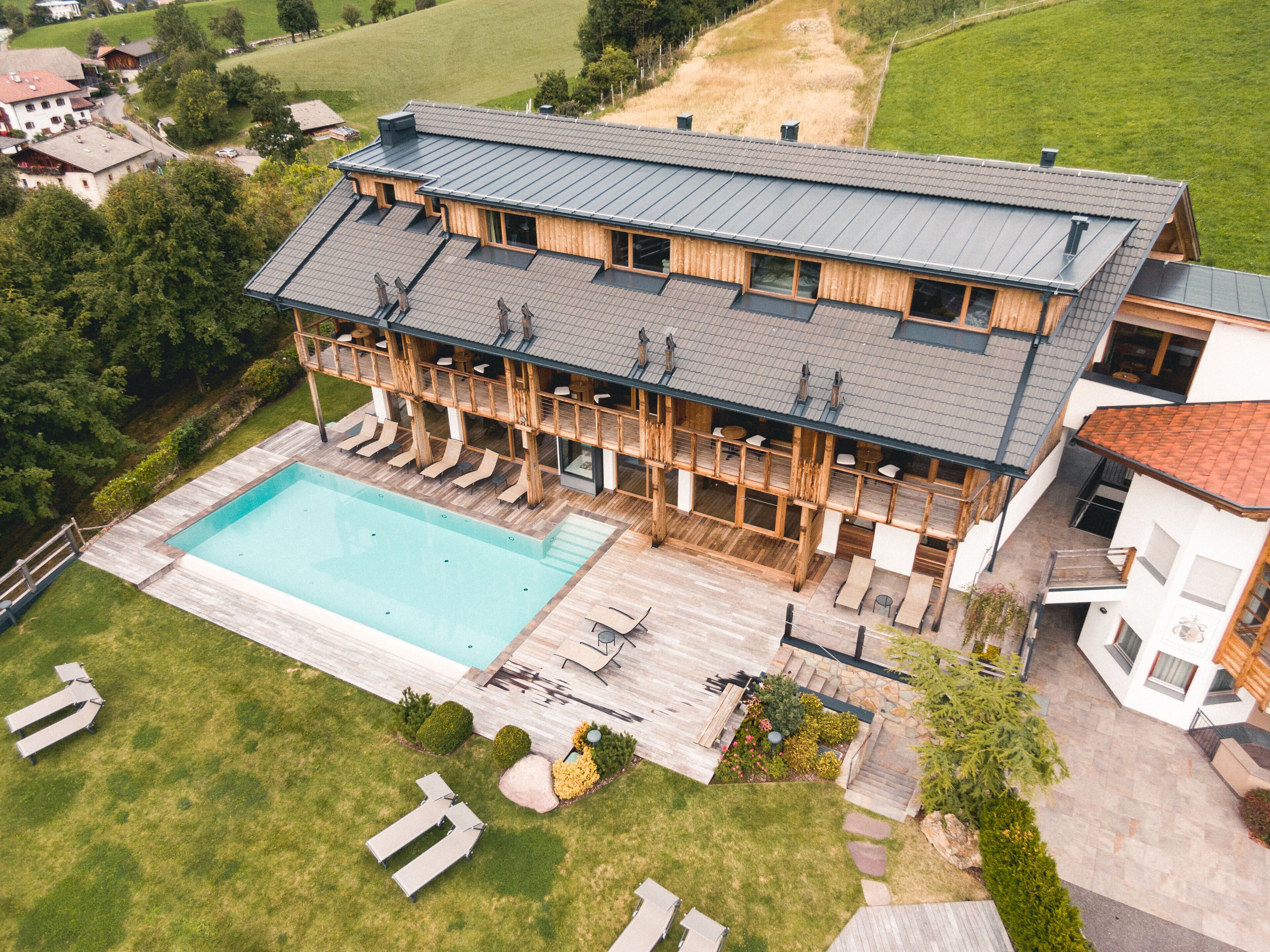 A large, modern building with a swimming pool, outdoor seating, and a deck area.