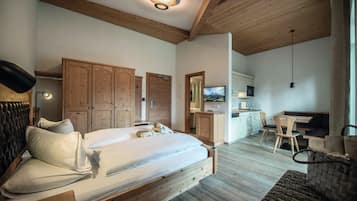 A bedroom with a wooden bed, a desk, a chair, and a kitchenette.