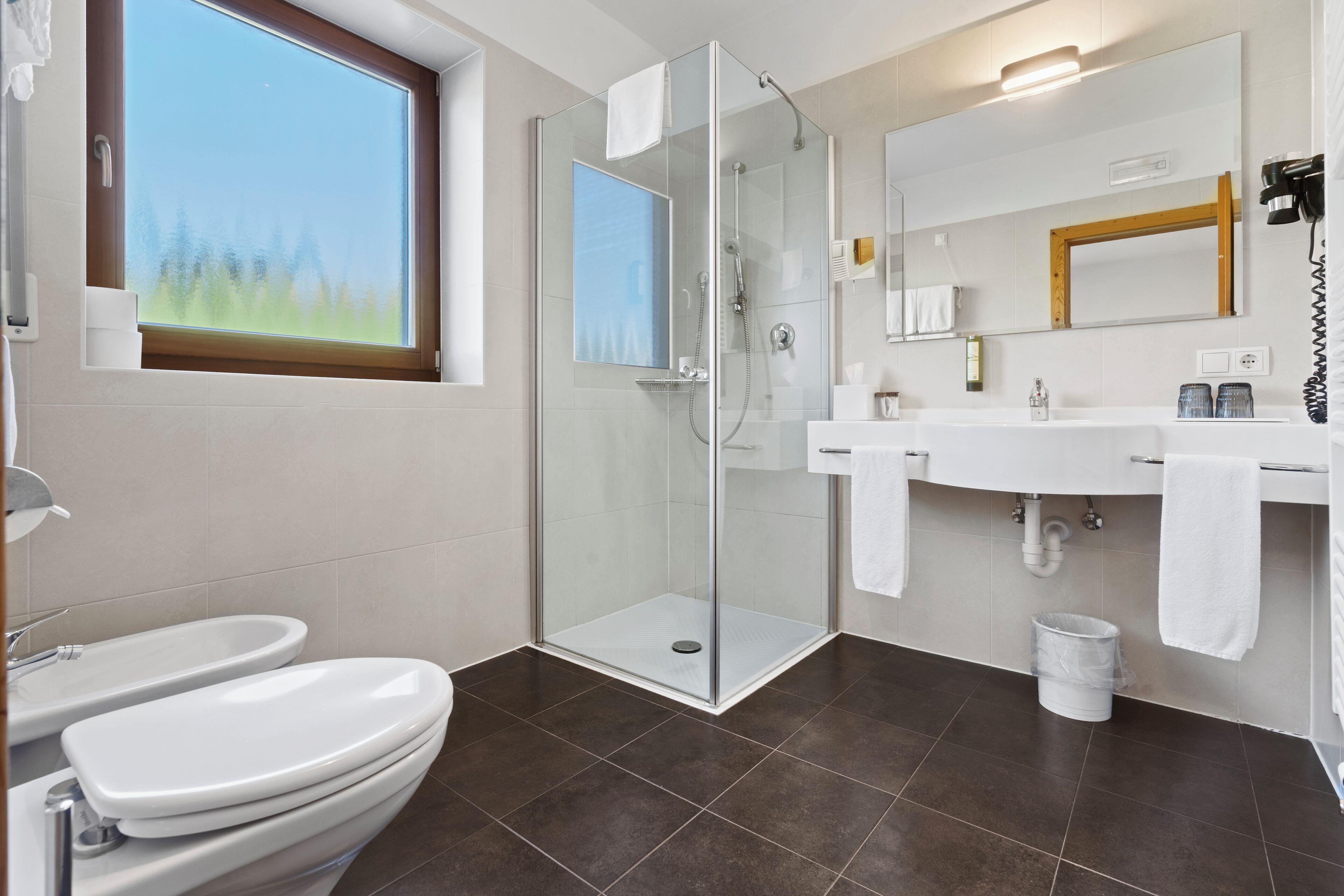 Une salle de bain moderne avec une douche à parois de verre, des toilettes et un lavabo avec un miroir au-dessus.