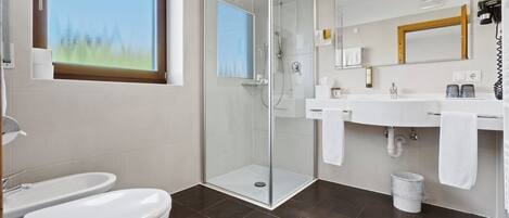 Une salle de bain moderne avec une douche à parois de verre, des toilettes et un lavabo avec un miroir au-dessus.