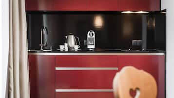 A modern kitchen with a black countertop, stainless steel appliances, and red cabinetry.