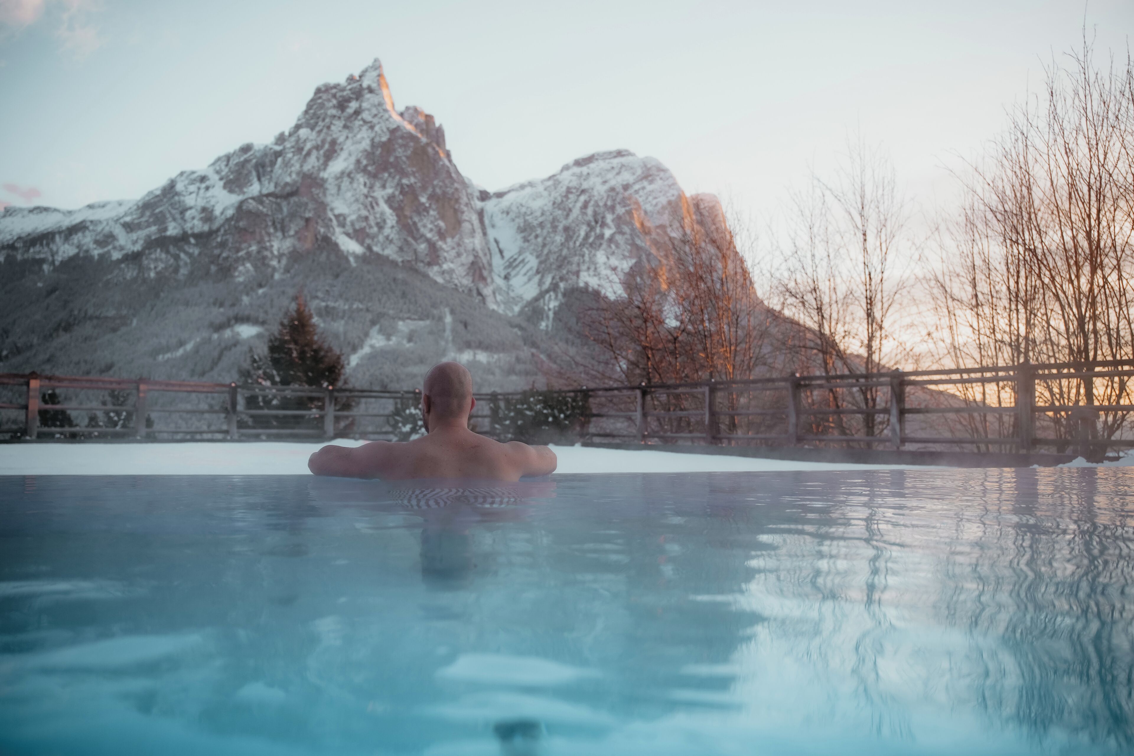 Une personne dans un jacuzzi, avec une chaîne de montagnes en arrière-plan.