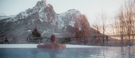 A person in a hot tub with a mountainous backdrop.
