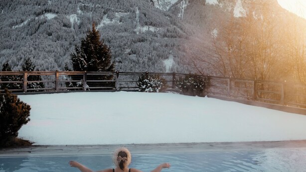 A person in a swimming pool with a mountainous landscape in the background. - Sonus Alpis - Adults Only (Castelrotto)