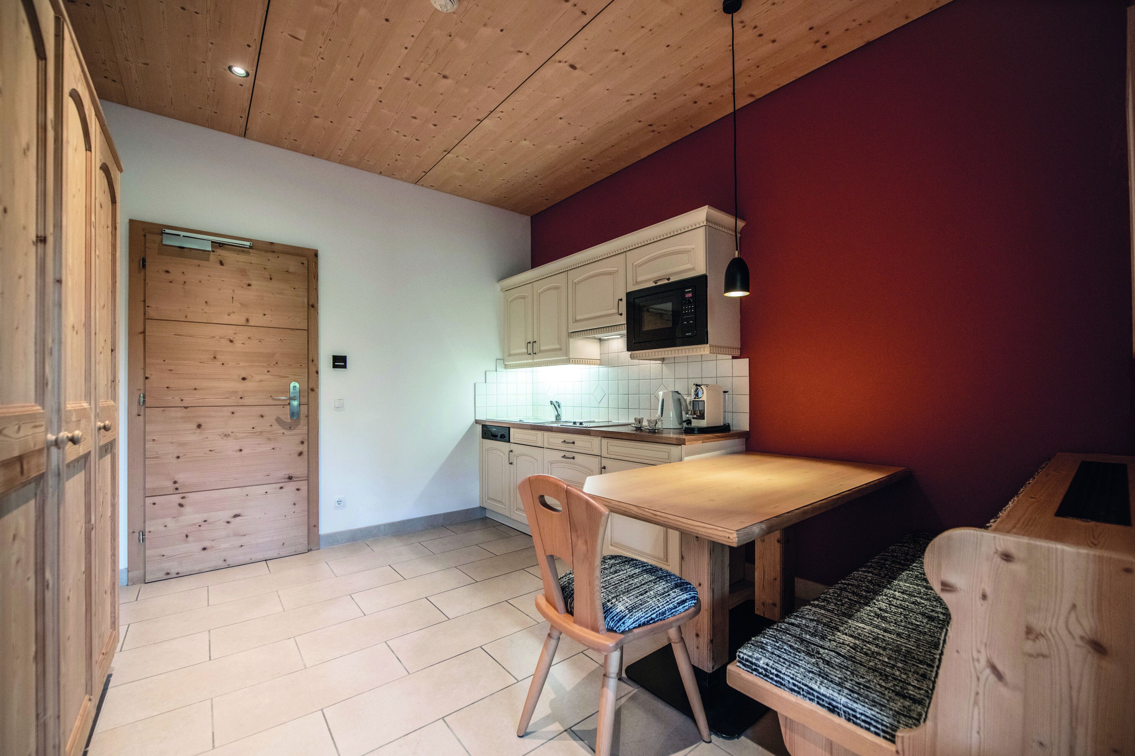 A kitchen with wooden cabinets, a microwave, and a dining table with a bench.