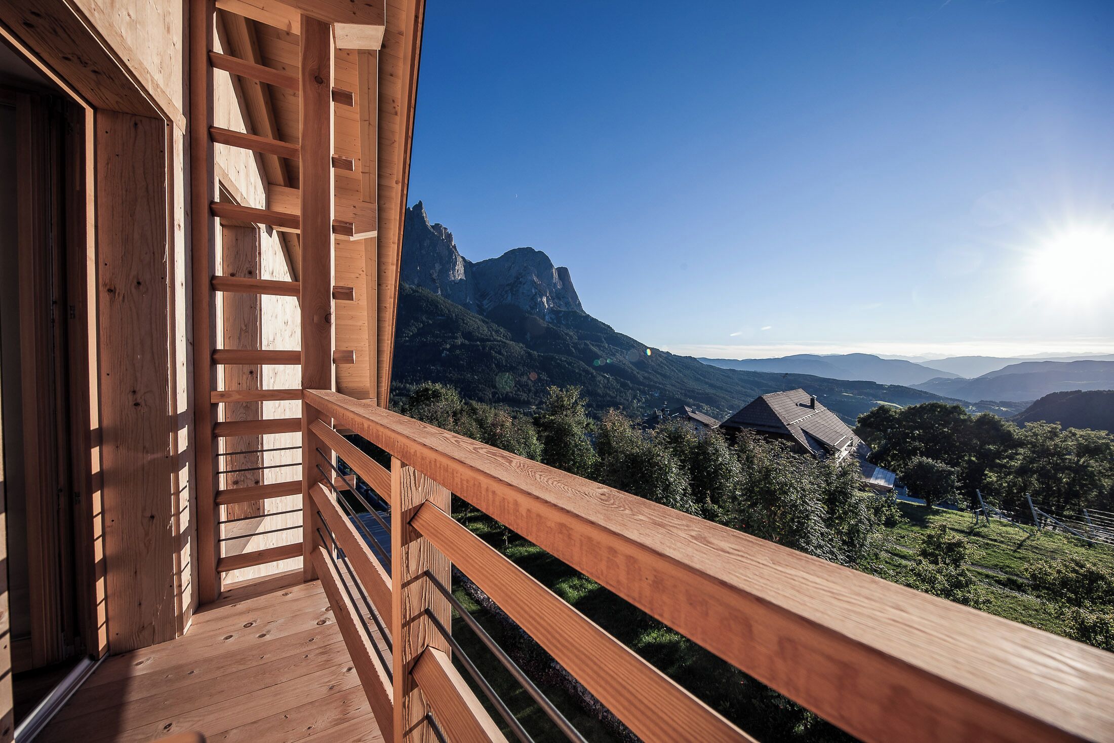A wooden balcony with a view of a mountainous landscape.