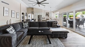 A modern living room with a sectional sofa, a coffee table, and a ceiling fan. - Pool, foosball, family fun at Always Summertime! (Scottsdale)