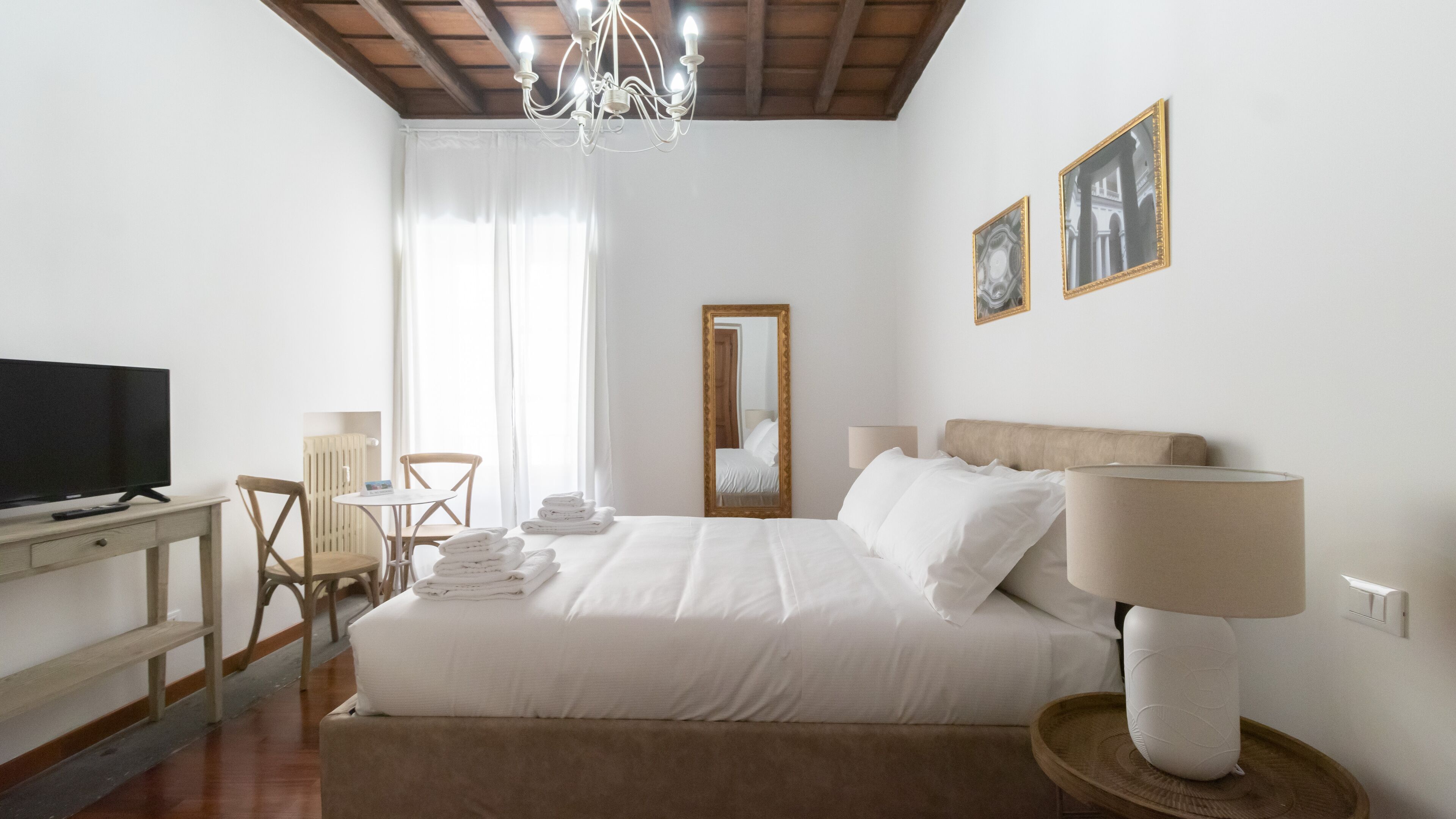 A hotel room with a bed, a television, a desk, and a chair.