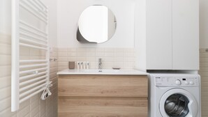 Un baño moderno con lavadora integrada, un espejo y un perchero.