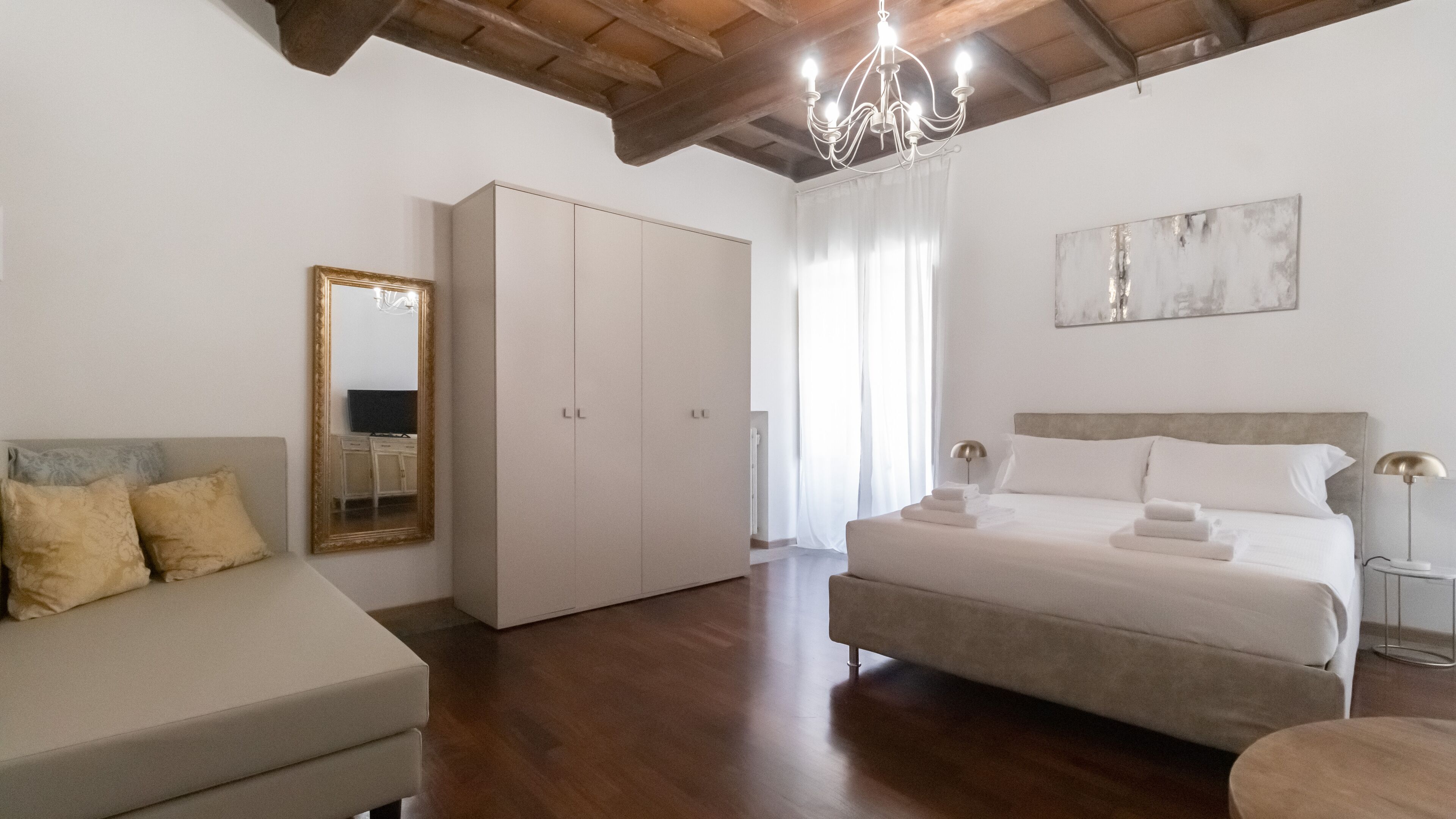Een slaapkamer met een bed, een kledingkast, een bank en een kroonluchter.