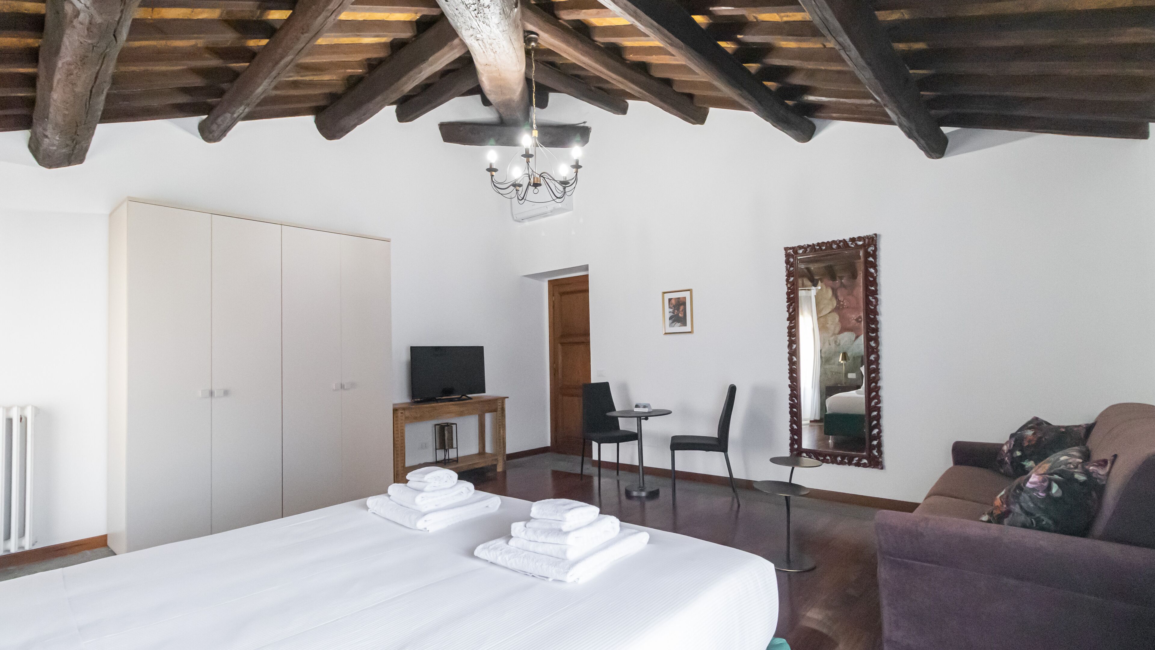 Une chambre à coucher avec un lit, une télévision, une chaise, une table et un miroir.