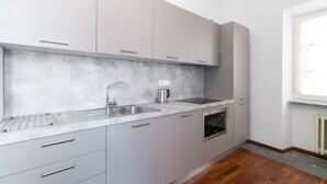 Una cocina moderna con armarios grises, un fregadero de acero inoxidable y un horno empotrado.