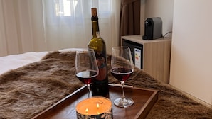 En træbakke med et lys, to vinglas og en vinflaske på en seng overdækket med pels.