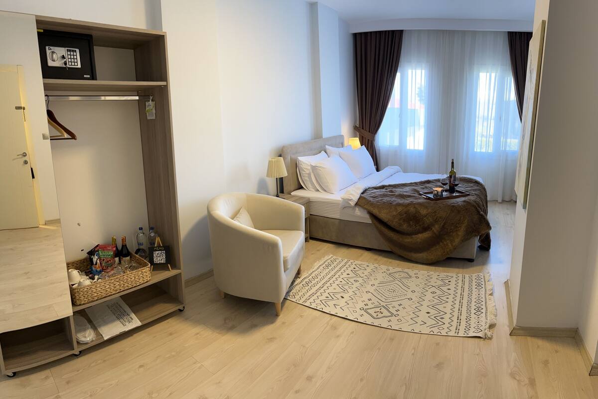 Une chambre d’hôtel avec un lit, une chaise, une petite table avec un plateau, un tapis et une armoire.