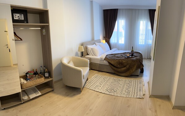Habitación de hotel con cama, una silla, una mesita con bandeja, alfombra y armario.