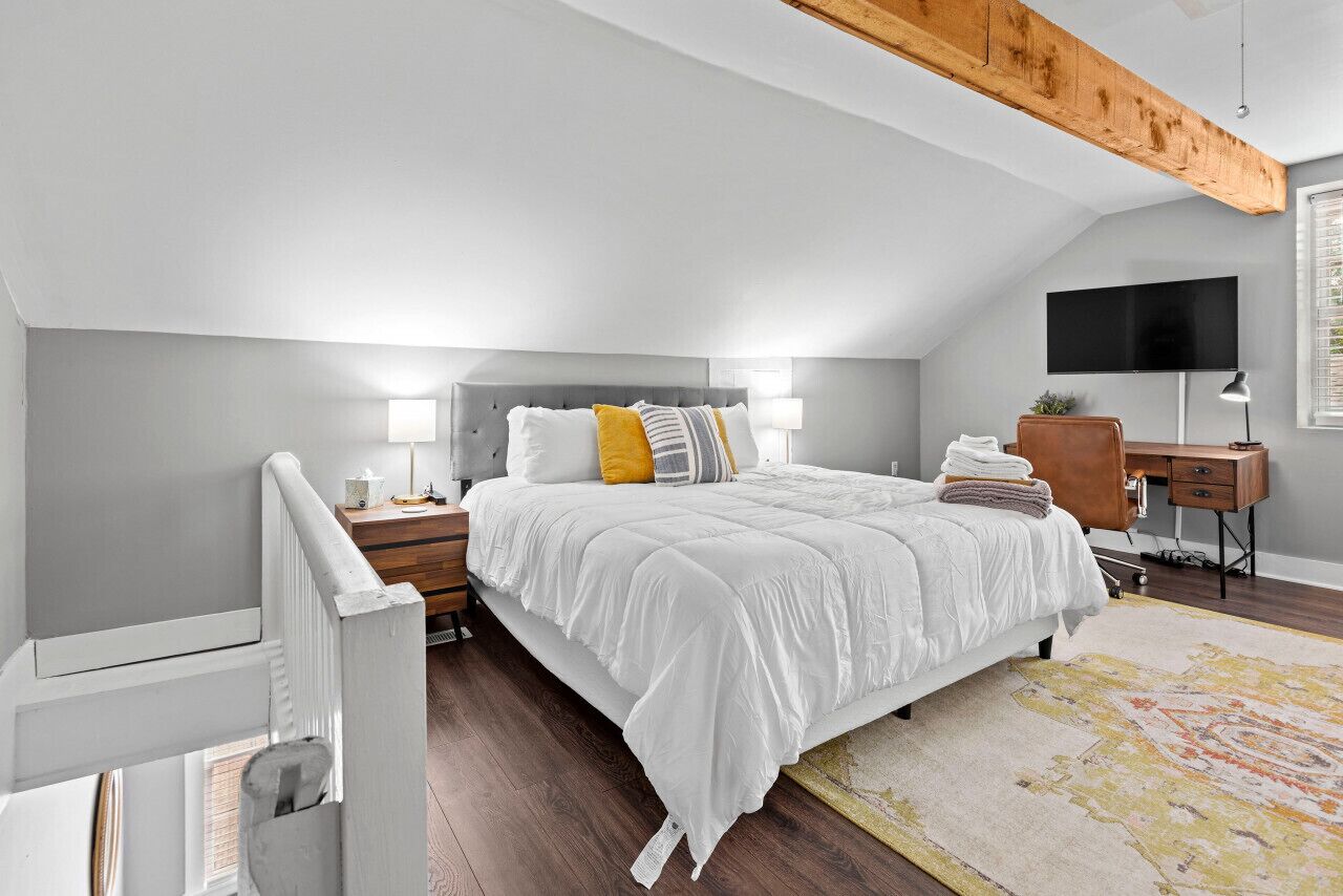 Un dormitorio con cama, mesitas de noche, un escritorio y televisor.