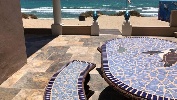 Un pati amb taules de mosaic i vista a l'oceà.