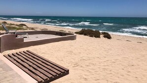 Una platja amb una zona d'estar de formigó i un tram de fusta.