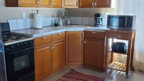 A kitchen with wooden cabinets, a gas stove, a microwave, and a coffee maker. - Hacienda De Sol y Luna- 2 bdrm Apartment (Playa Encanto)