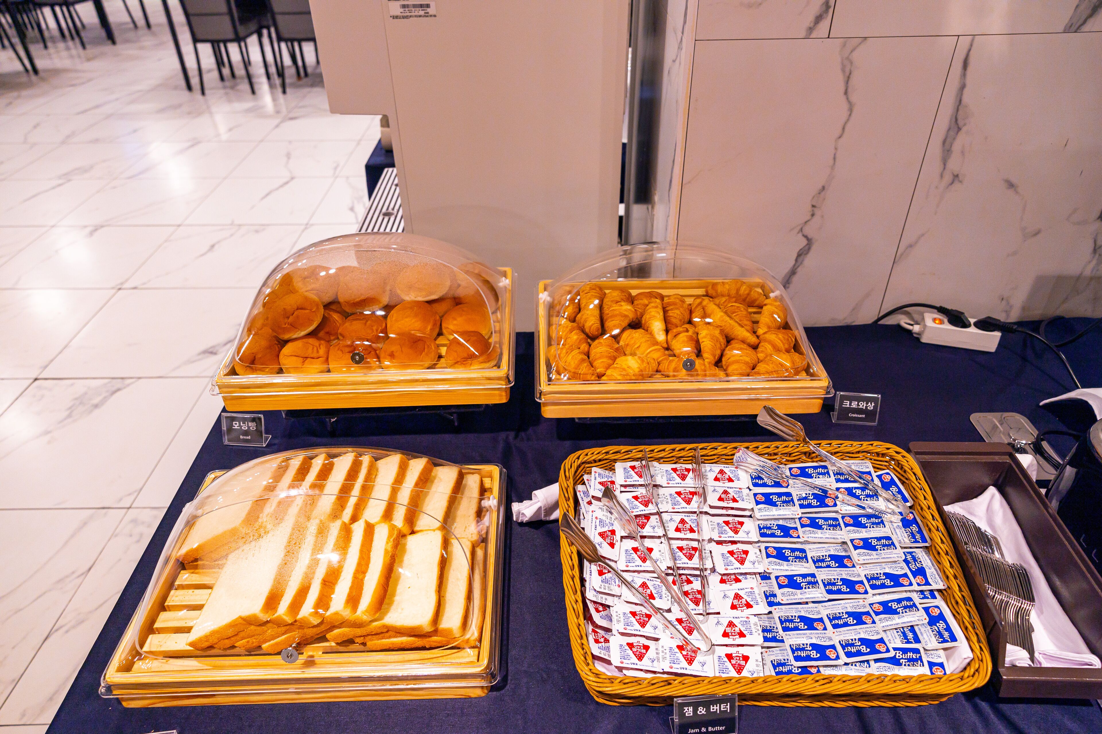 Un bufé con diferentes opciones de comida, incluyendo pan, pastelería y paquetes de mantequilla.