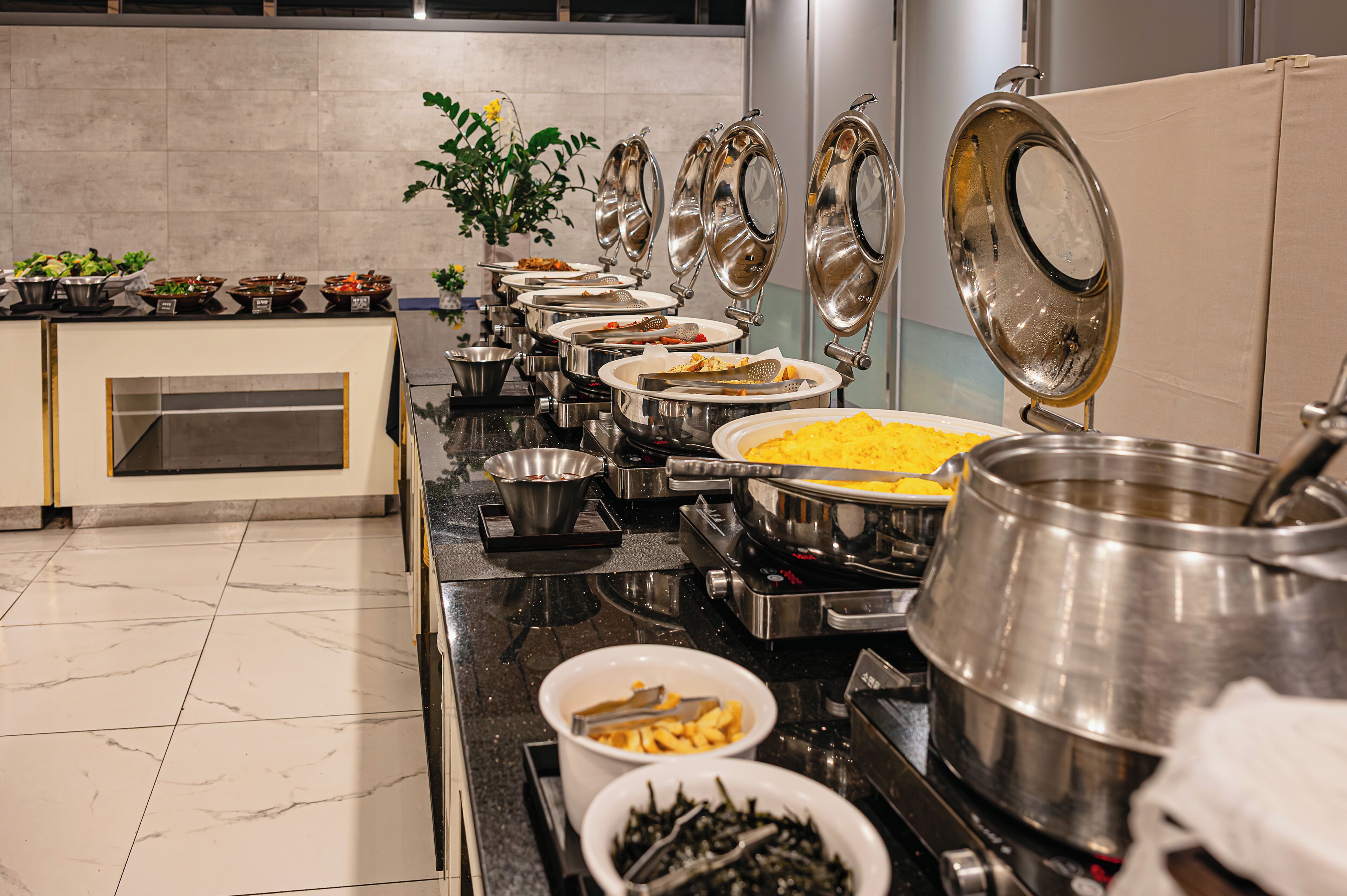 A buffet setup with various food items and serving utensils.