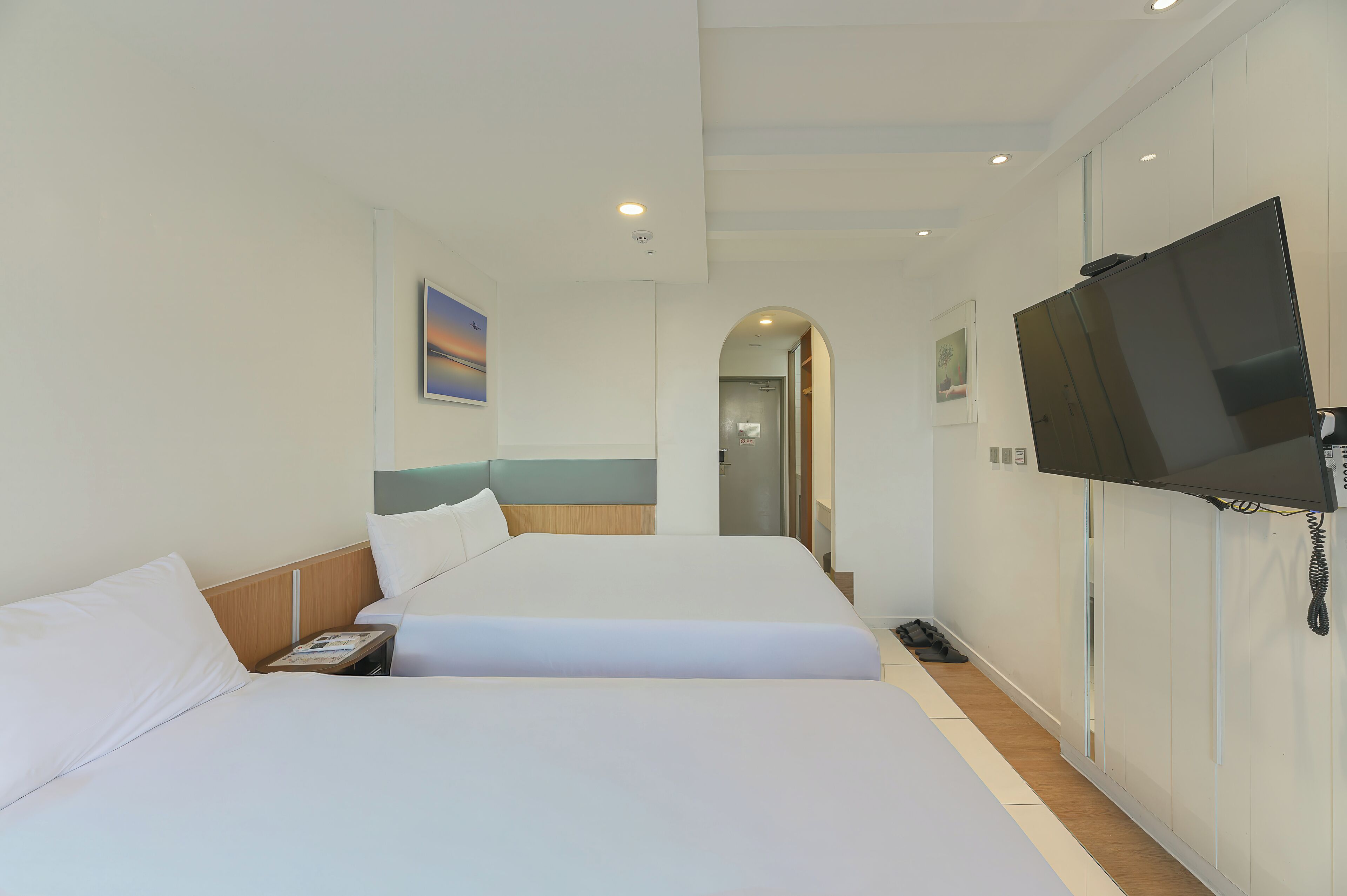 Ein Hotelzimmer mit zwei Betten, einem Fernseher und einem Telefon.