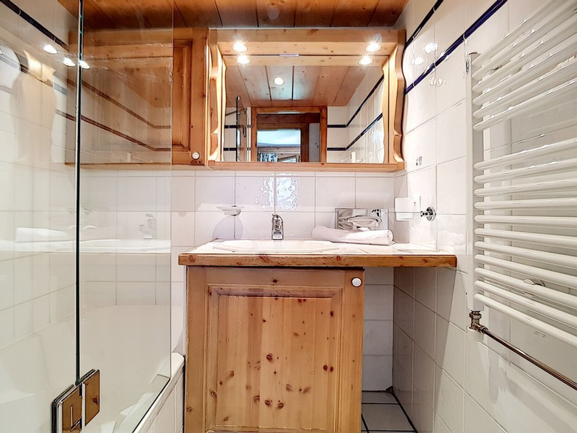 Une salle de bain avec un meuble-lavabo en bois, un miroir au-dessus du lavabo et une cabine de douche en verre.