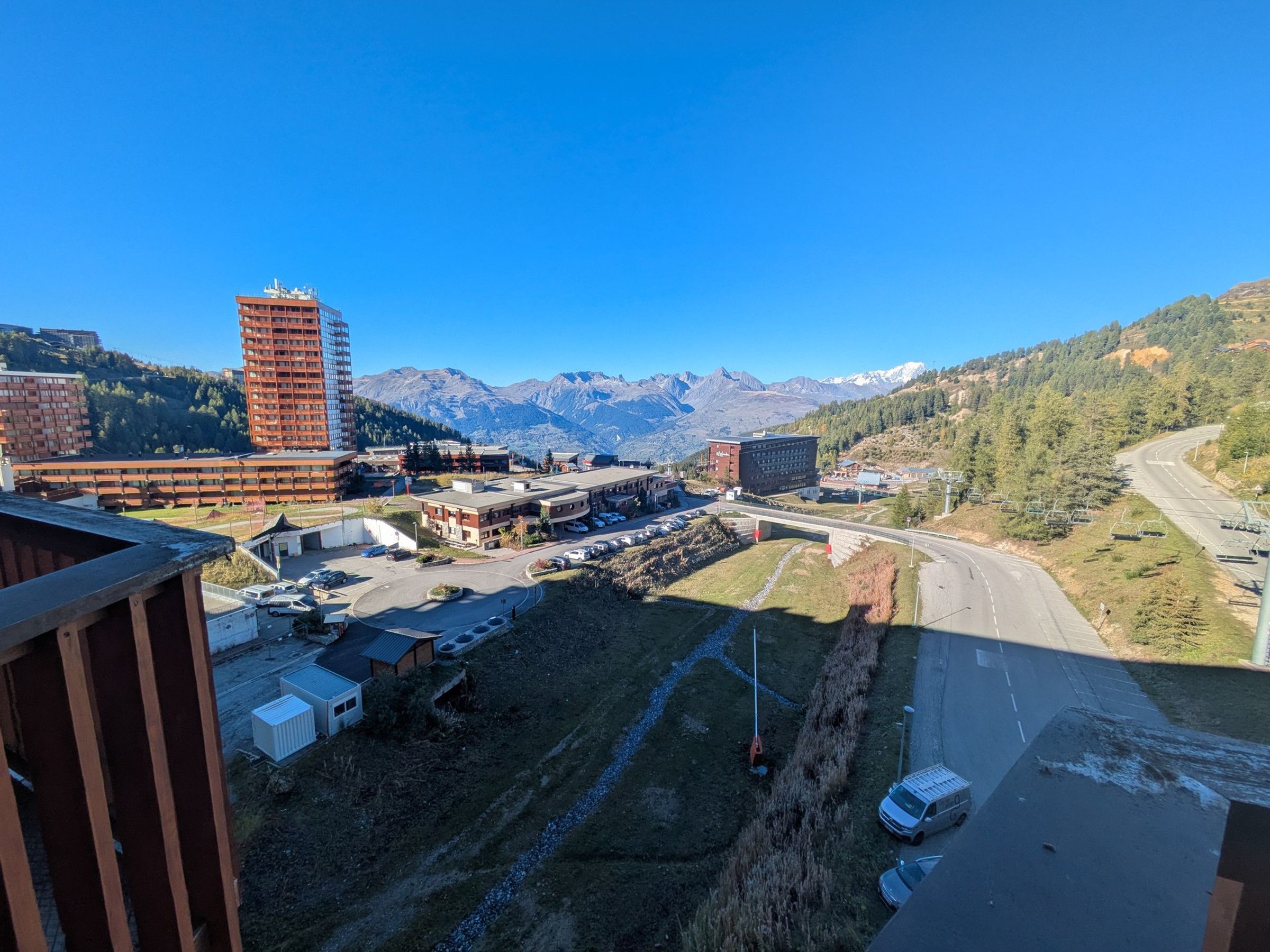 A mountainous landscape with a road, buildings, and a parking area.
