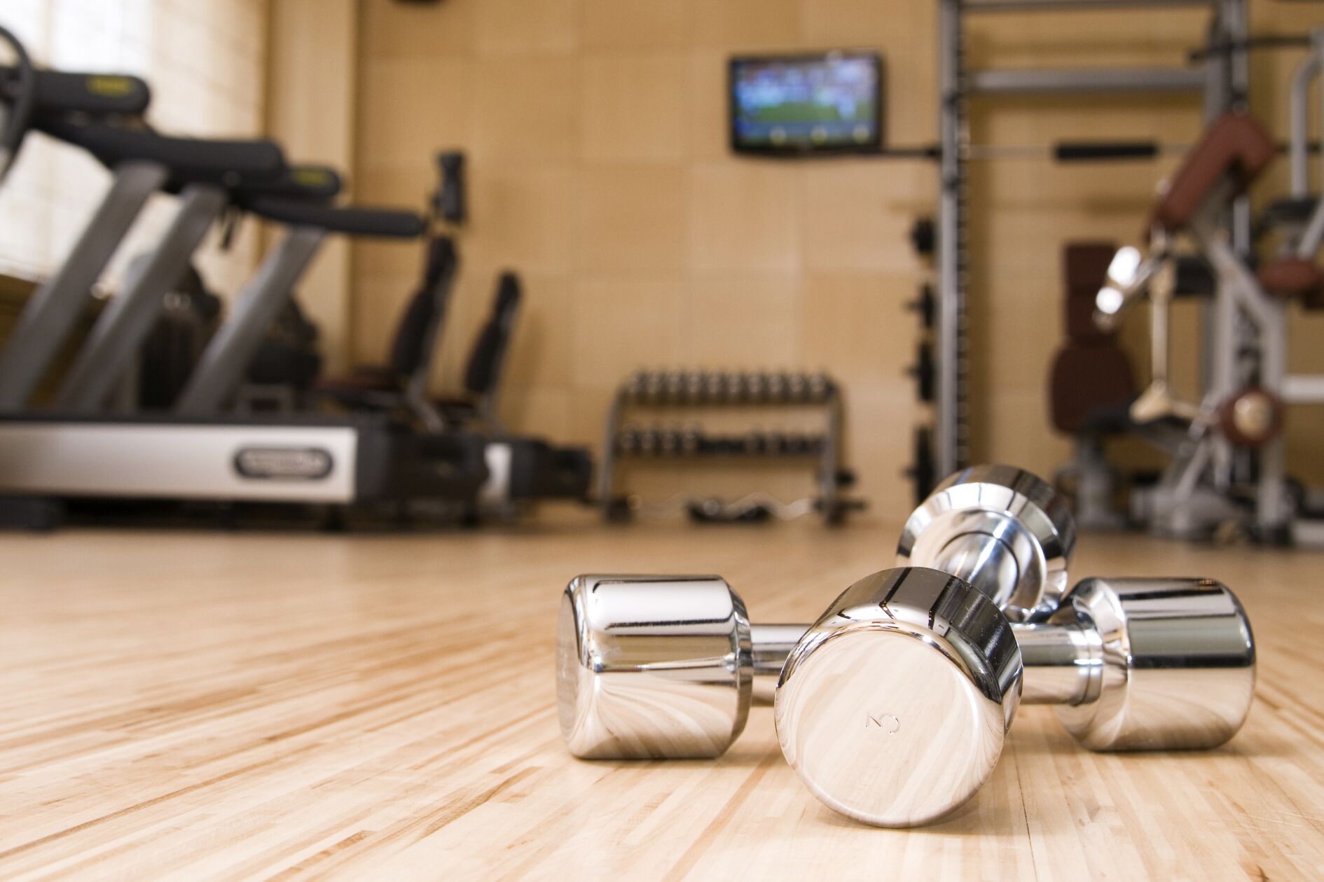 Un gimnasio con equipo de ejercicio, incluyendo mancuernas y una cinta de correr.