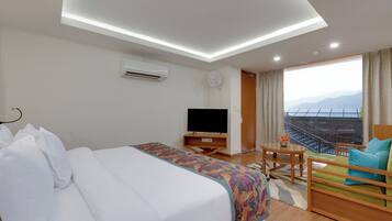 Ein Hotelzimmer mit einem großen Bett, einem Fernseher, einem Balkon mit Blick und einem kleinen Tisch mit Blumenvase.