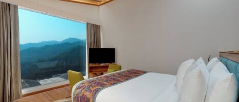 Ein Hotelzimmer mit einem großen Bett, einem Flachbildfernseher, einem Schreibtisch und Bergblick durch das Fenster.