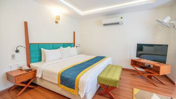 Una habitación de hotel moderna con cama, mesita de noche, televisor y un pequeño escritorio.