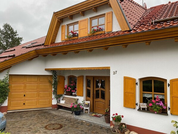 A two-story house with a tiled roof, wooden shutters, and a garage.