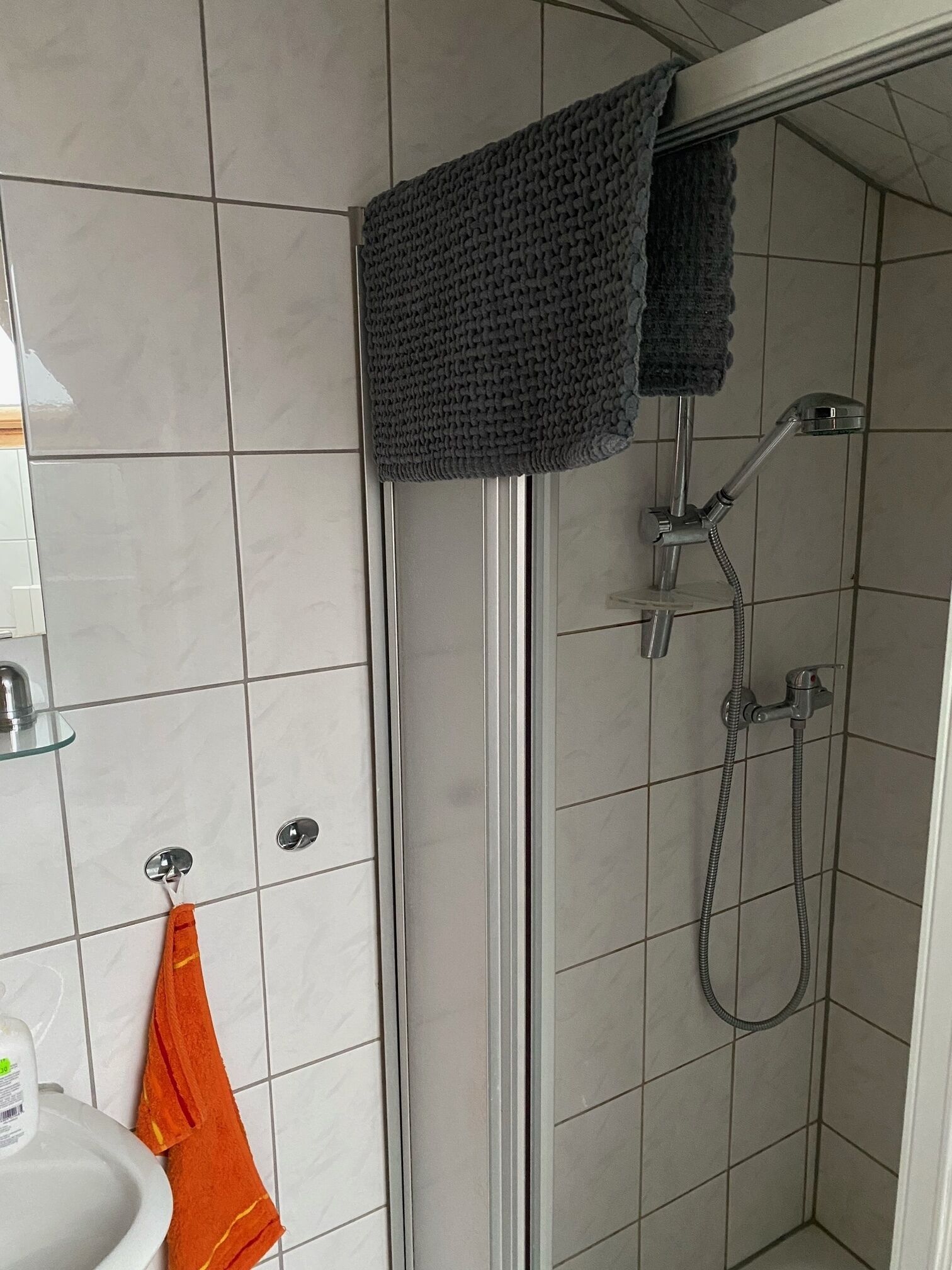 A bathroom with a shower, a sink, and a towel rack.