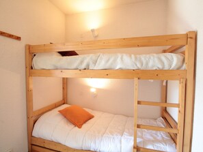 Cozy bunk bed room with a comfortable upper and lower bunk, featuring a wall-mounted light fixture.