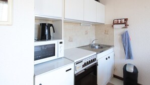 A compact kitchen with a microwave, stove, sink, and a coffee maker on the countertop. - Studio for 4 pers, 100m from slopes, near shops (Les Carroz d'Arâches)