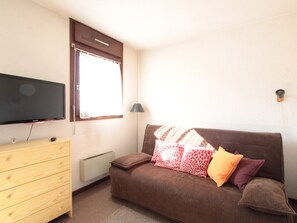 Cozy living space with a sofa, flat-screen TV, and wooden dresser.