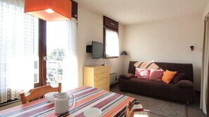 A cozy living room with a striped table, a brown sofa, and a television on the wall. - Studio for 4 pers, 100m from slopes, near shops (Les Carroz d'Arâches)